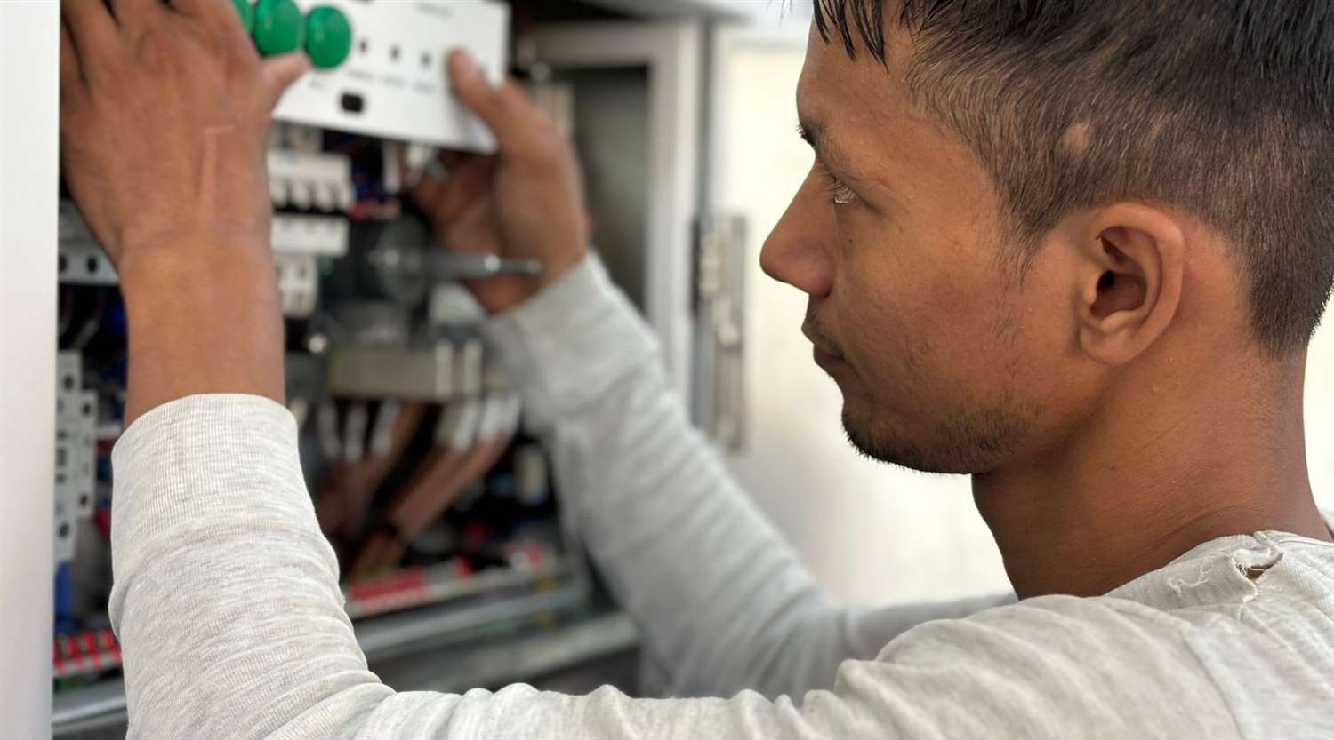 Electrician working inside a breaker panel